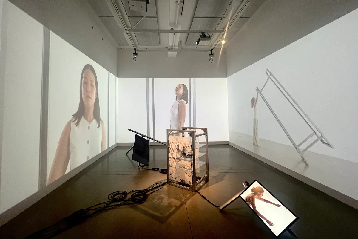 A digital media installation with video on three walls, computer screens on the floor and other metal structures