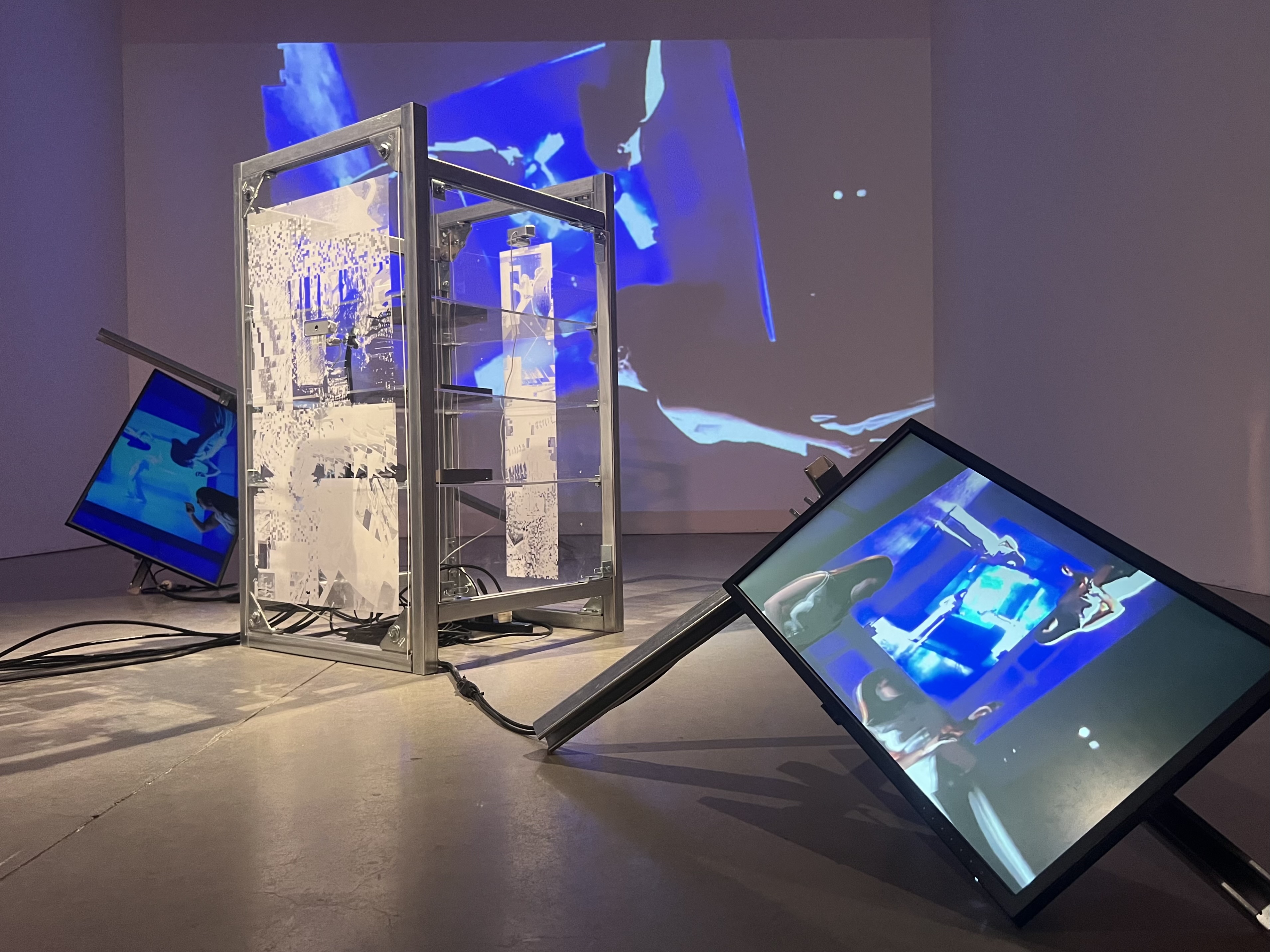 Multiple video screens of dancers awash in blue light