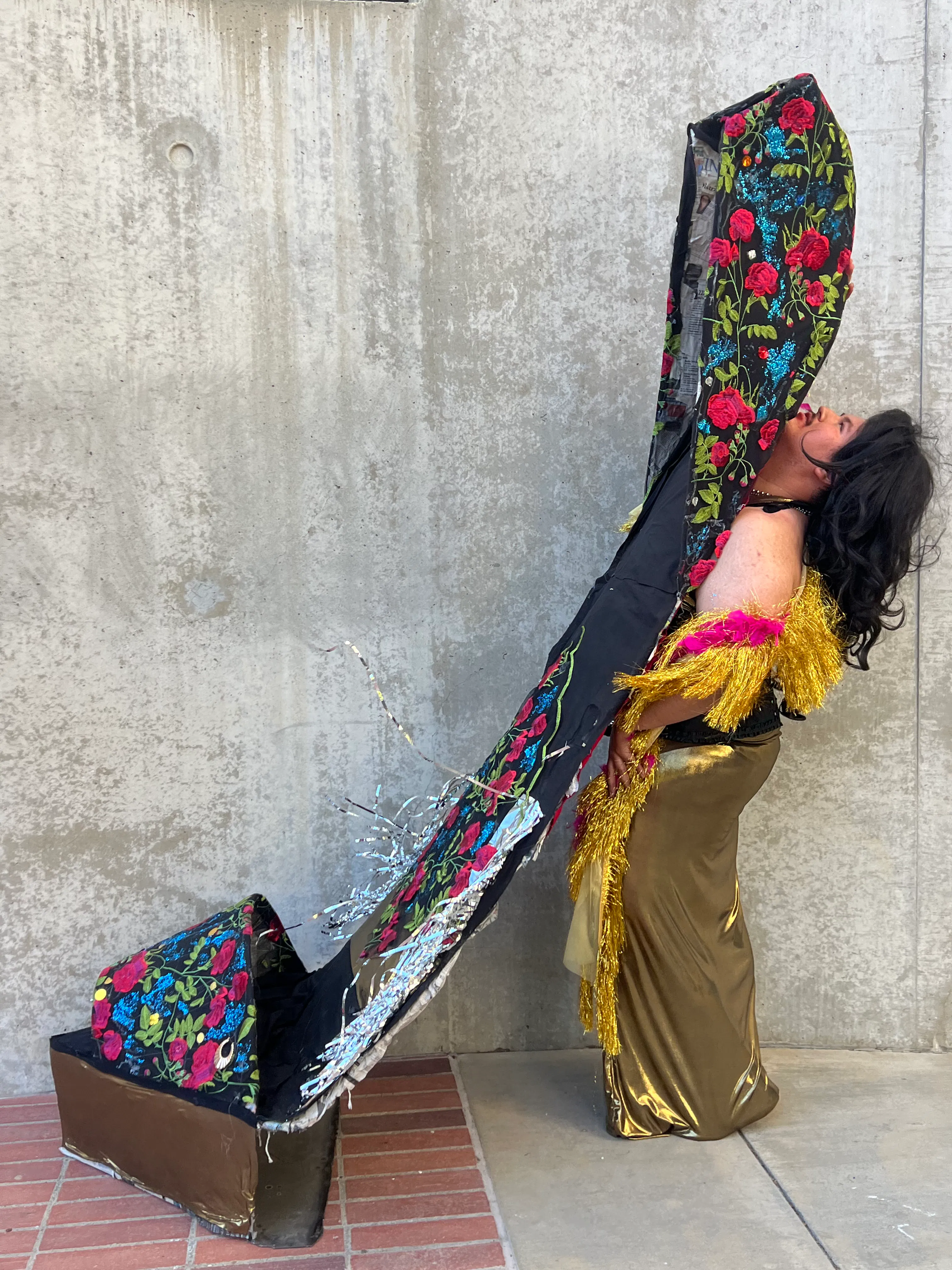 A man in drag serves as the high heel portion of a larger-than-life shoe with a rose design