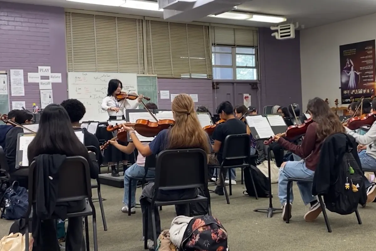 A violin teacher instructs a group of students
