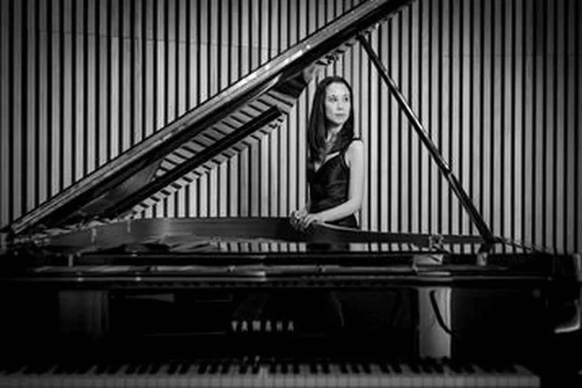 Portrait of performer Elizabeth Schumann standing near a piano