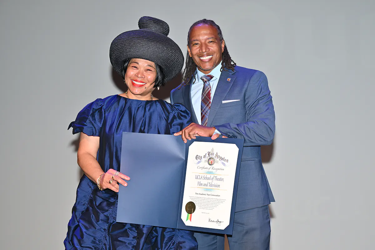 Dean Celine and Konstantine Hatcher pose together holding a commendation from the LA Mayor's office