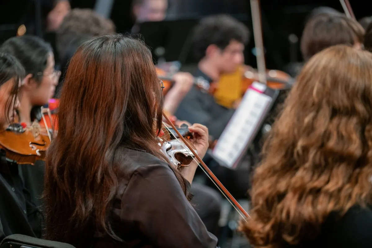 Close up of several violinists performing with the UCLA philharmonia in Schoenberg Hall