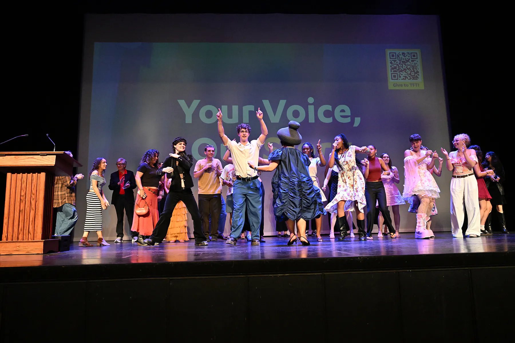 A large group of students dance together on stage