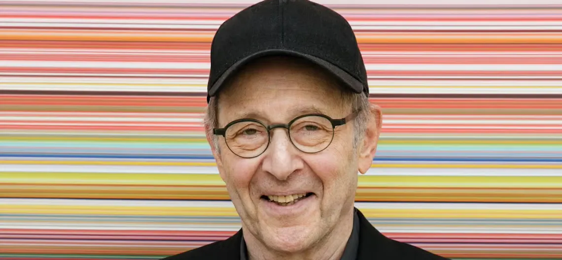 Portrait of steve reich posing against a colorful striped background
