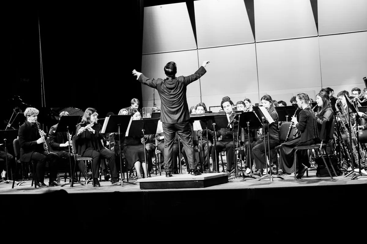 Black and white image of an orchestra onstage with the conductor in motion