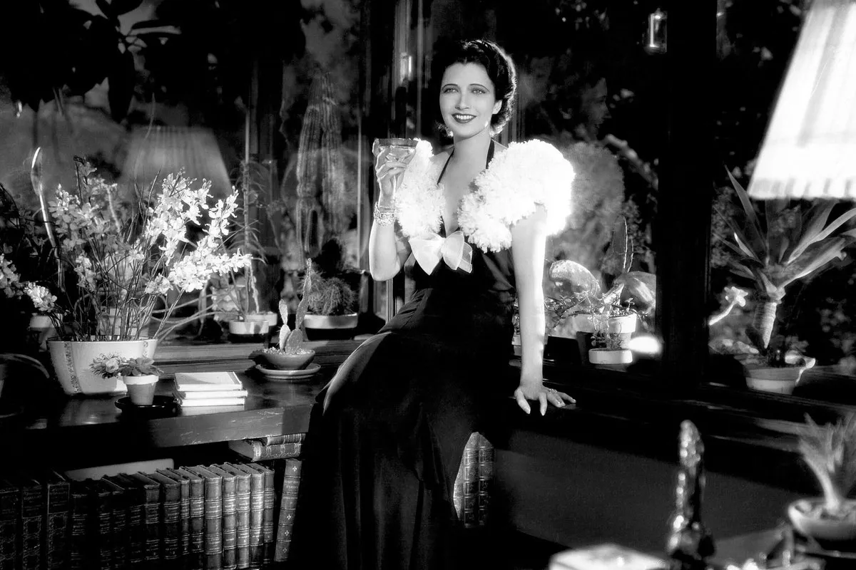 a woman in a fancy dress sitting holding a glass