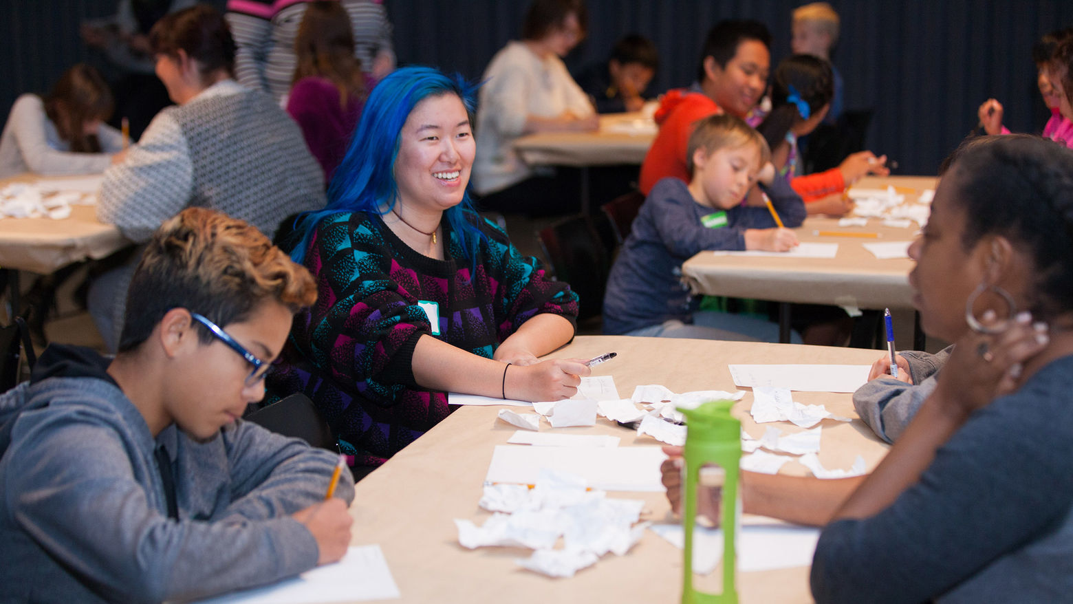 A group of kids sit at a table, writing