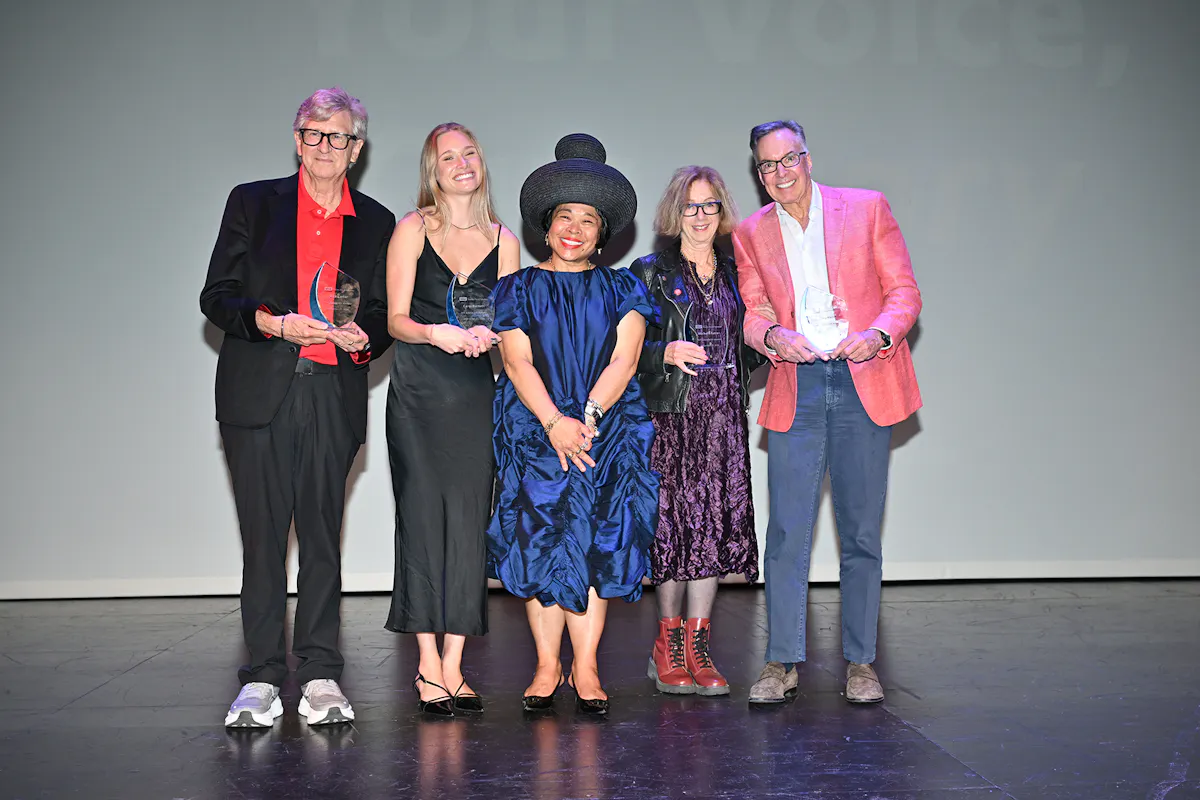 A group of people pose holding awards on stage