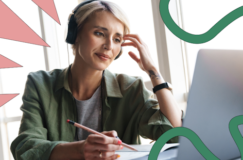 Woman with headphones on sitting in front of a laptop, writing notes