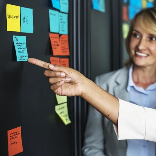 Two women in an office prioritising different tasks on sticky notes