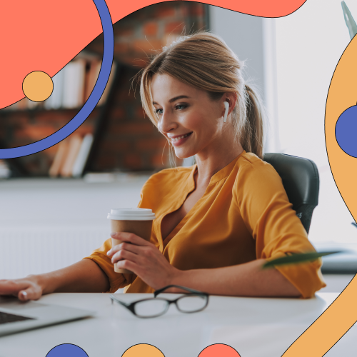 Woman drinking a coffee and working on her laptop while smiling