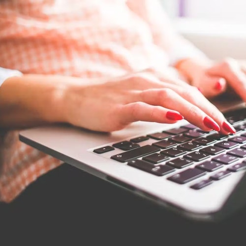 Woman with red nails typing on a laptop