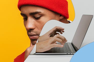 Man in a red beanie typing on a laptop