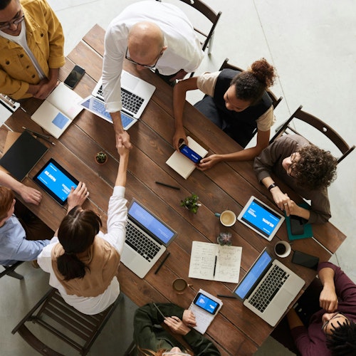 People sitting around a desk in a meeting shaking hands