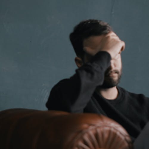 Man sitting on a couch with his head in his hands