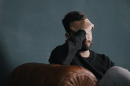 Man sitting on a couch with his head in his hands