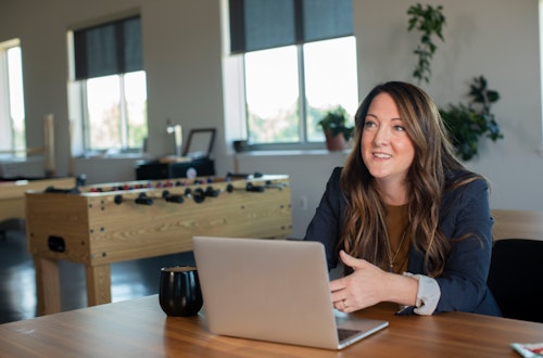 Woman sitting at her laptop drining a cup of coffee