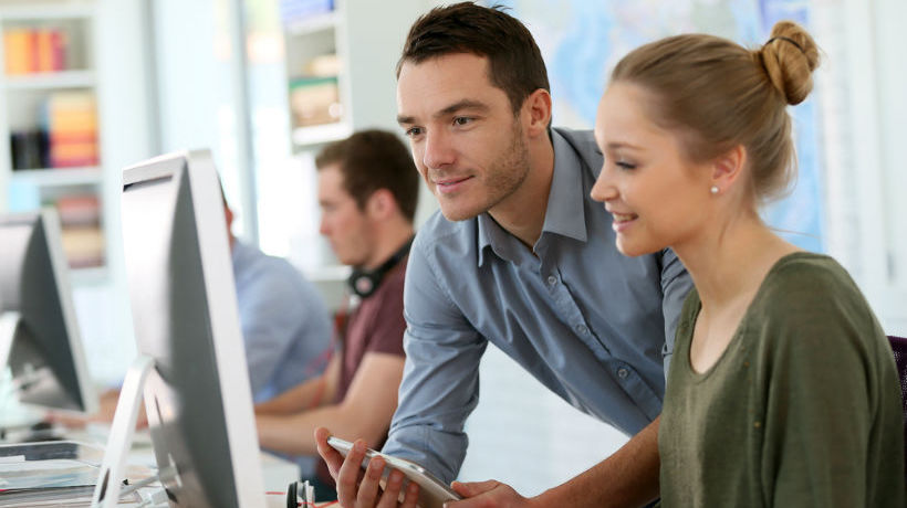 Two people talking in front of a computer, representing leadership skills