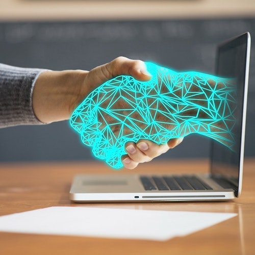 Person shaking hands with a digital arm coming out of a laptop, symbolising unconscious bias in technology