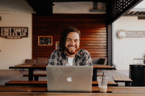 Man sitting behind a laptop smiling (front on view)