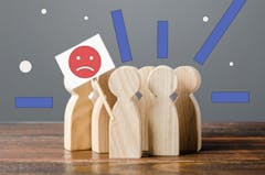 Grouping of wooden peg figurines with sad face graphic