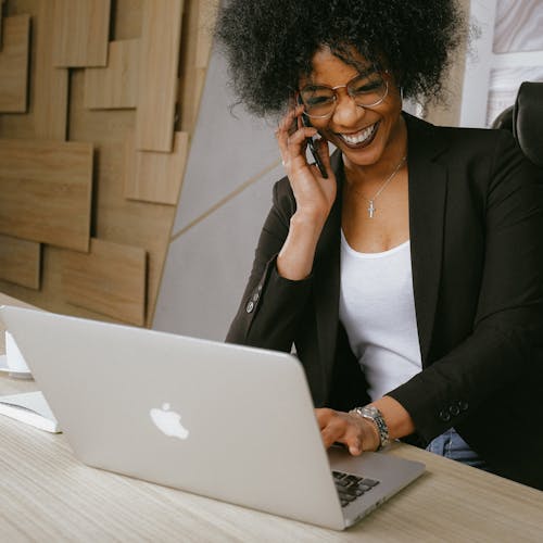 Woman sitting in her office smiling and looking at her laptop