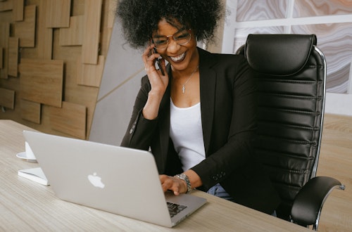 Woman sitting in her office smiling and looking at her laptop