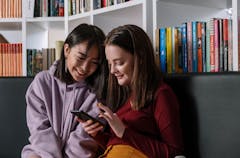 Young people sitting in a library looking at their phones