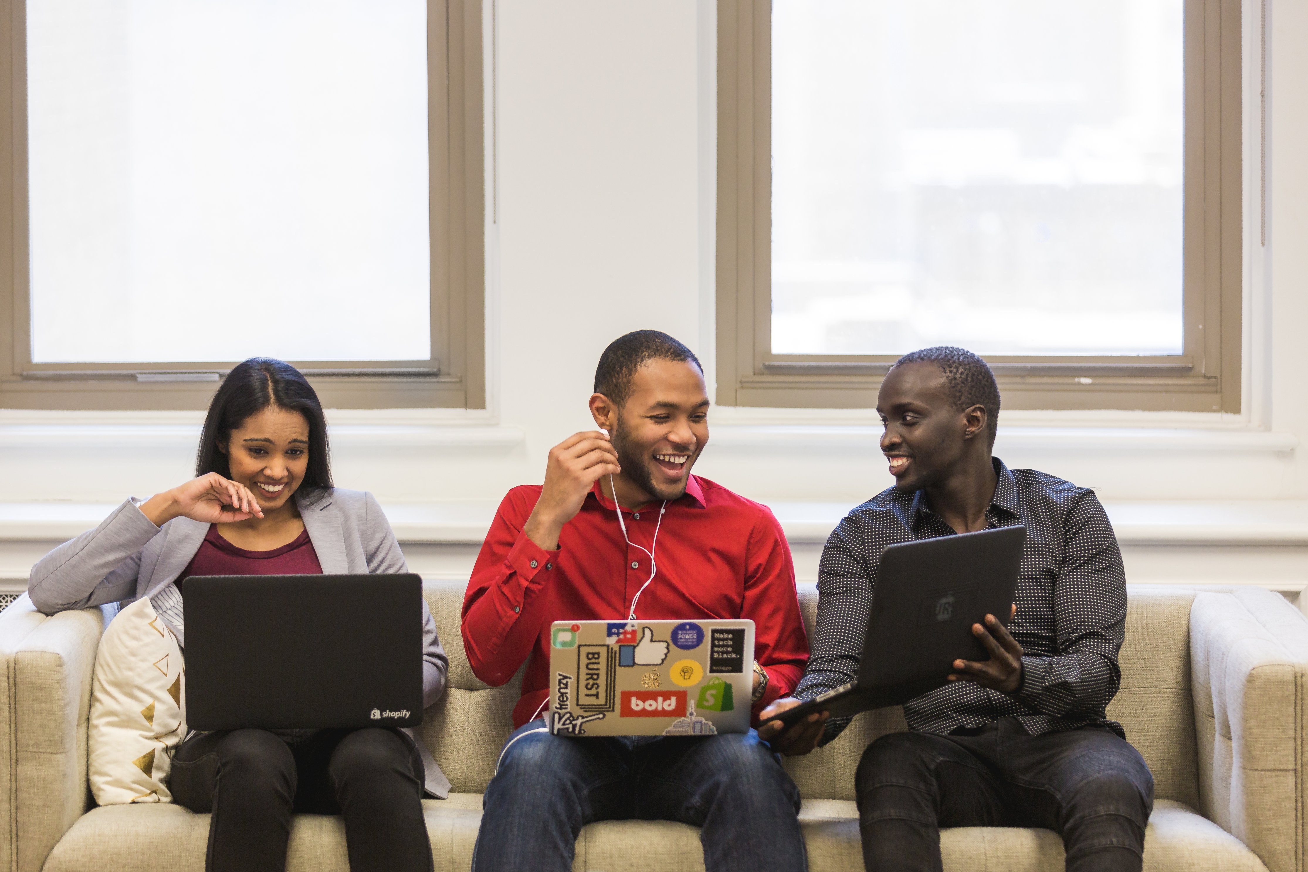 Three people sitting on a couch sharing information with each other