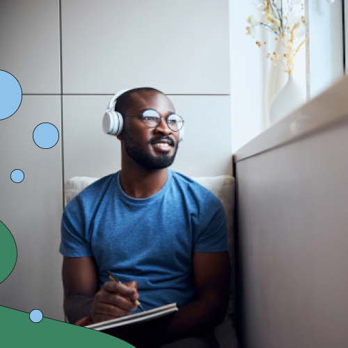 Smiling man wearing headphones and taking notes 