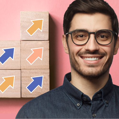 Man smiling next to building blocks pointing upwards