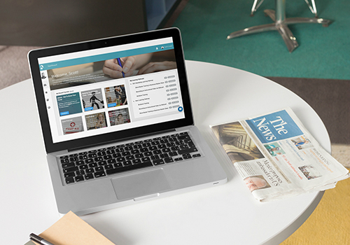 Laptop and newspaper sitting on a table