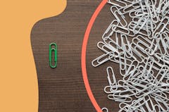 Collection of paperclips and one green single paperclip