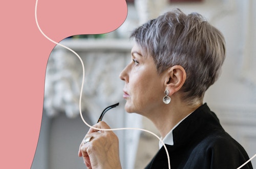 Woman holding a pair of glasses to her lip and staring out the window