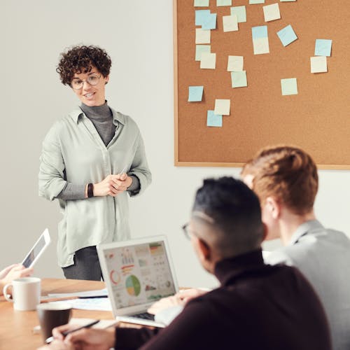 Woman standing up talking to a group of colleagues