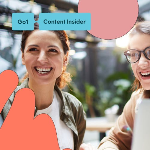 Two women working collaboratively with a laptop and big smiles