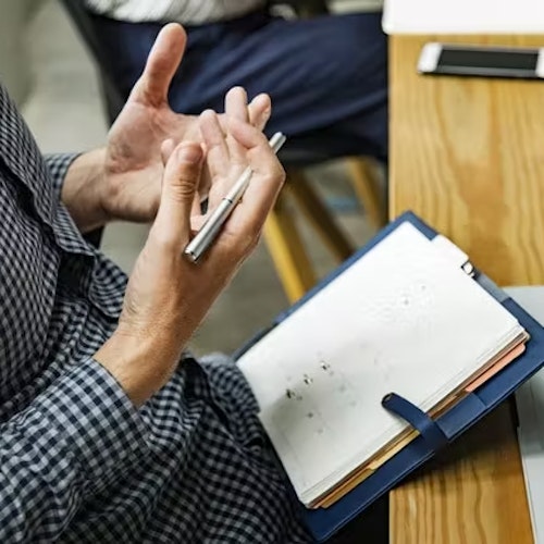 Man staring at his hands while writing in a notebook