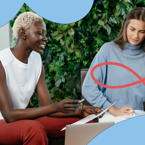 Two women having a conversation and taking notes in the workplace