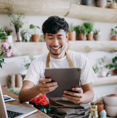 Image of a smiling man in a plant shop holding a tablet.