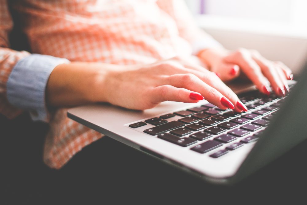 Woman with red nails typing on a laptop