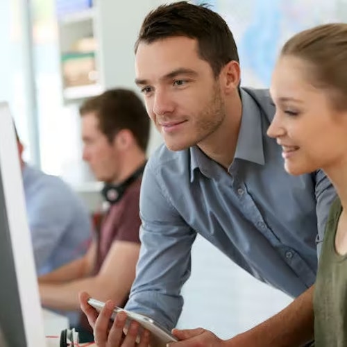 Two people talking in front of a computer, representing leadership skills