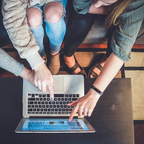 Three women pointing at a laptop screen