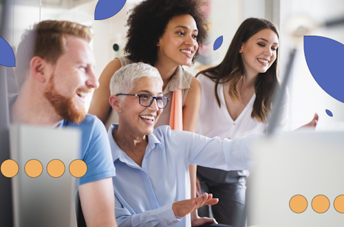 Four people sitting or standing around a computer smiling