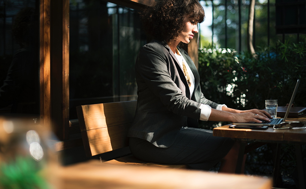 Woman sitting at an outdoor table working on a laptop