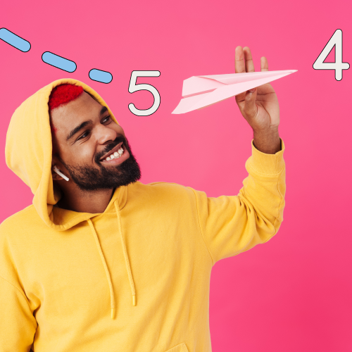 Man in a yellow hoodie holding a paper airplane with a pink background