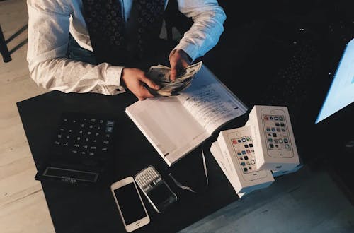 Man sitting at a desk next to a calculator counting money