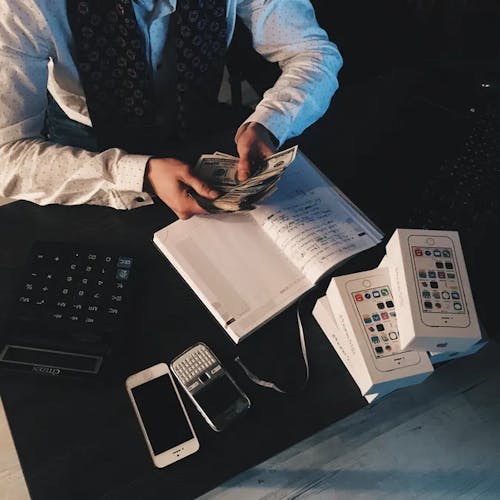 Man sitting at a desk next to a calculator counting money