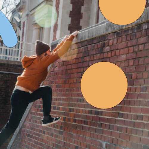Person climbing over brick wall