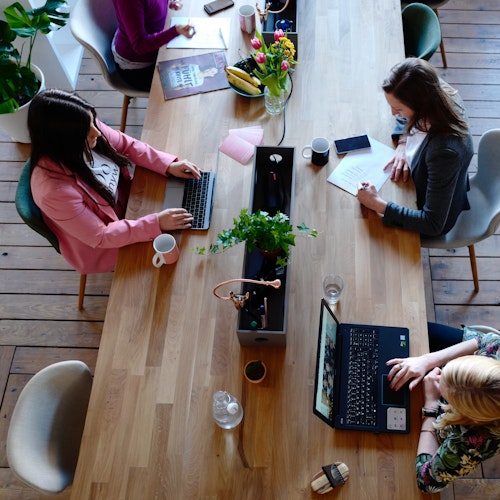 Female co-workers sitting together in an office, representing a sustainable learning culture